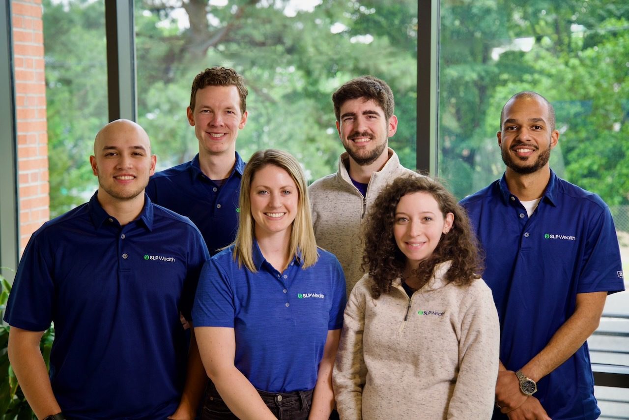 6 members of the SLP Wealth team posing in company polos and sweaters. The team is diverse, including men, women, and people of various ethnicities.
