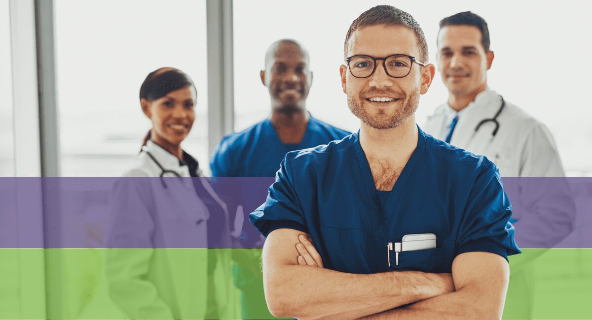 four healthcare workers standing, very proudly. One male healthcare worker with arms crossed, smiling big